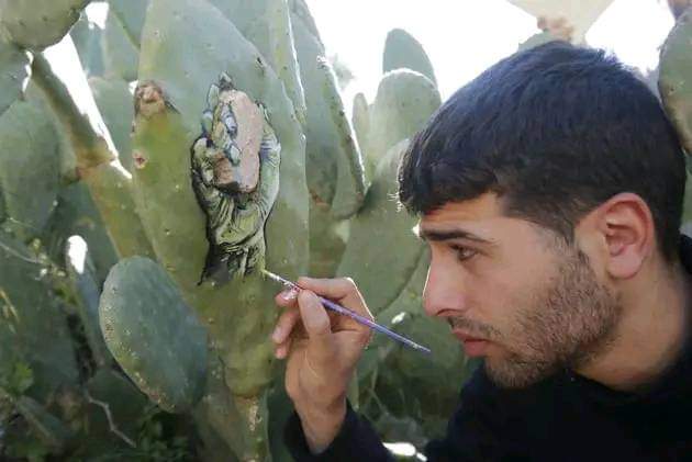 رسام فلسطيني يجسد صبر شعبه بالنحت على أشجار الصبّار