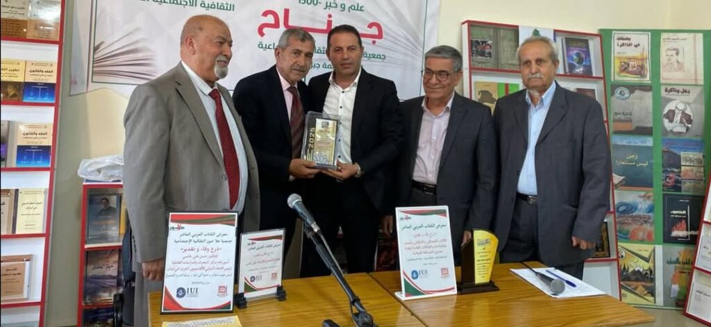 الاعلامي الشاعر محمد درويش يتسلم درع التقدير من سفير السلام العالمي حسين غملوش في معرض الكتاب